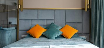 pexels-photo-6492390-6492390 Soft bed with turquoise blanket and multicolored pillows placed in modern bedroom with curtains and hanging decorative lamps at home